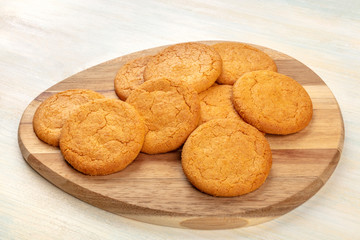 A photo of a heap of gingersnaps on a wooden tray