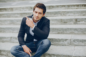 Man in a stylish suit. Businessman in a summer city. Male drinking a coffee