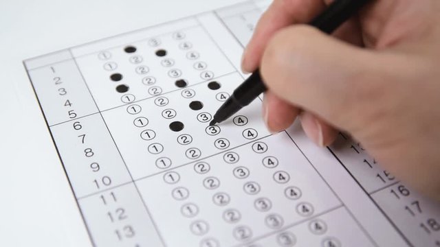 Man is filling OMR sheet handing with pen.