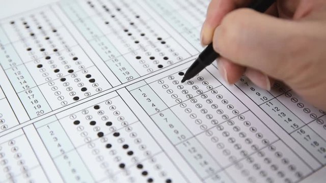 Man is filling OMR sheet handing with pen.