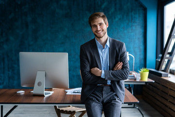 Businessman wearing modern suit and stands in contemporary office.