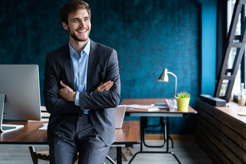 Businessman wearing modern suit and stands in contemporary office.
