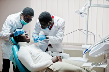 African american man patient in dental chair. Dentist office and doctor practice concept. Professional dentist helping his patient at dentistry medical. Drilling patient's teeth in clinic.