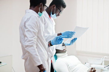 African american man patient in dental chair. Dentist office and doctor practice concept. Professional dentist helping his patient at dentistry medical. Pointing at teeth X-ray.