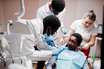 Fototapeta premium Multiracial dentist doctors team. African american man patient preparing for surgery. Scared face of the patient.