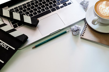 office stuff with Movie clapper, laptop, smartphone, tablet, coffee cup, pen, notepad and documents on the wood table top view shot.