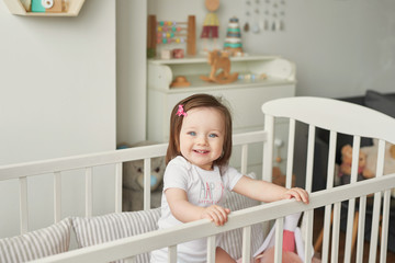 girl in a crib with toys in the children's room