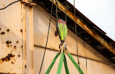 old girder crane with large iron hook lifts  heavy load on  slings
