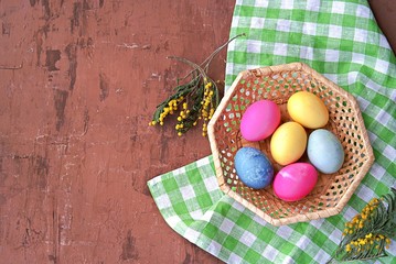 Multi-colored Easter eggs in a wicker basket on a brown background. Selective focus. Happy Easter concept.