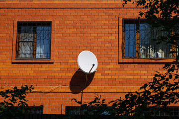 Detail of red brick house with decorative window grates and white satellite dish