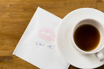Obraz na płótnie Canvas Napkin with a kiss and coffee cup on wooden background.