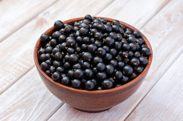 Ripe black currant in a clay dish.