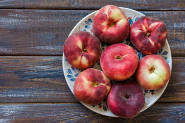 Ripe flat variety peaches in a clay dish.