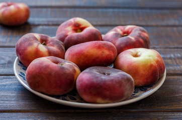 Fototapeta na wymiar Ripe flat variety peaches in a clay dish.