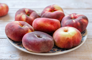 Ripe flat variety peaches in a clay dish.