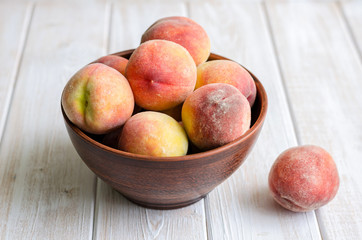 Ripe peaches in a clay dish.