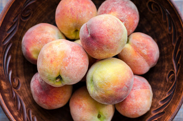 Ripe peaches in a clay dish.