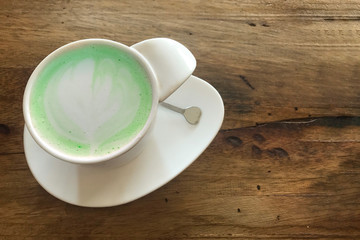 heart art shape design on the top of hot japnese green tea matcha milk cup on dark wood table background.