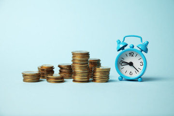 Alarm clock and golden money coins, capitalization. Time is money concept, payment.