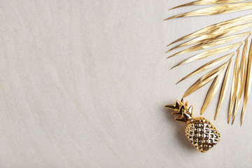 Golden tropical leaf and pineapple on light background