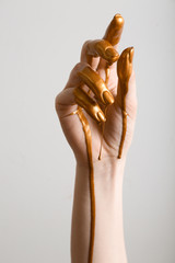 Female hand with golden paint on skin against light background