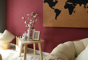 Cotton flowers on wooden table near big world map on wall