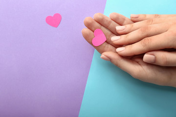 Female hands with confetti on color background