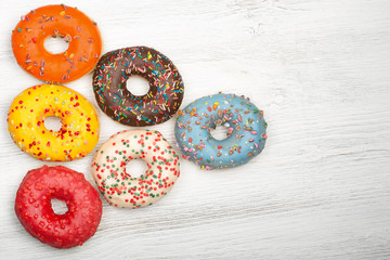 Obraz na płótnie Canvas Set of donuts of various colors with space for text. White wood background.