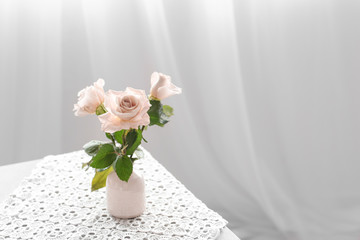 Vase with fresh rose flowers on table in room