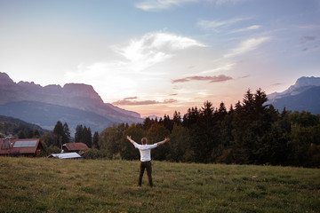 Male tourist raised his hands up against backdrop of Alps mountains in France Chamonix Mont Blanc