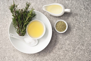 Oil with fresh and dry rosemary on grey table