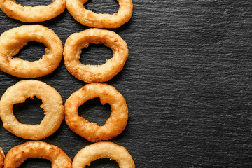 Tasty onion rings on dark background