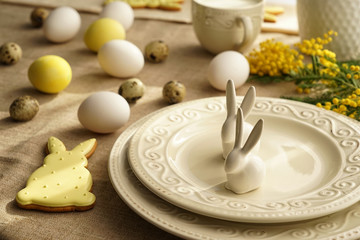 Plates with bunnies, Easter cookie and eggs on table