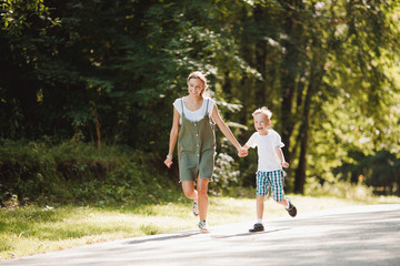 Younger brother and elder sister are running around park, holding hands, having fun, laughing, smiling. Concept Happy family