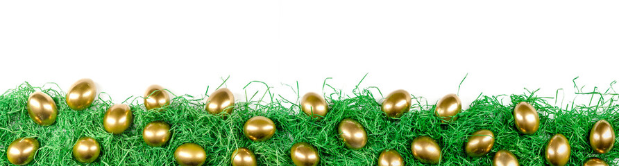 panorama of golden easter eggs on green easter grass, isolated with white background