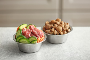 Bowls with dry and fresh pet food on table