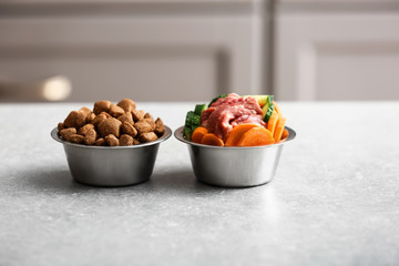 Bowls with dry and fresh pet food on table