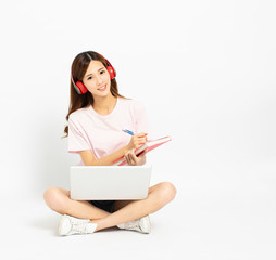 Happy student girl sitting on the floor using laptop