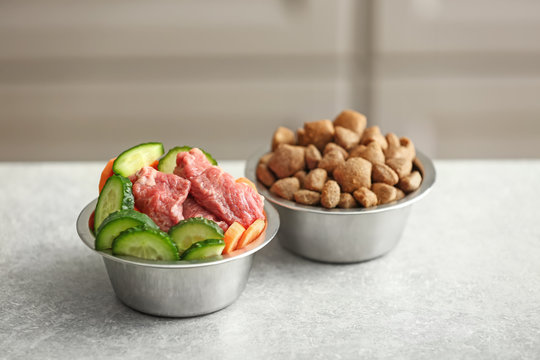 Bowls with dry and fresh pet food on table