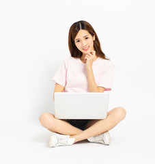 Happy young woman sitting on the floor using laptop