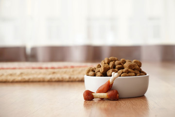 Bowl with dry pet food on floor