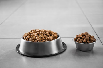 Bowls with dry pet food on floor