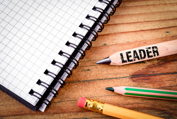 LEADER text on pencil. Business success concept. Stationery on an old wooden background