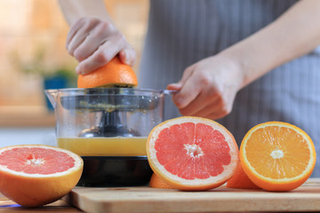 Woman's hands is holding a orange half and making juice