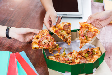 Hands taking pizza slices