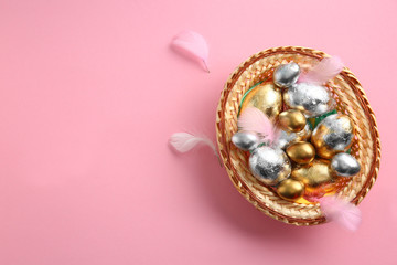 Wicker tray with beautiful Easter eggs on color background