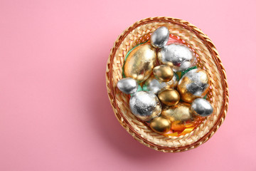 Wicker tray with beautiful Easter eggs on color background