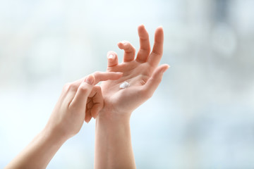 Hands of young woman applying cream at home