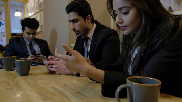 Handheld shot of business people in an informal space they are busy occupied on their mobile phone screens and ignore each other and remain unmoved and unaffected 