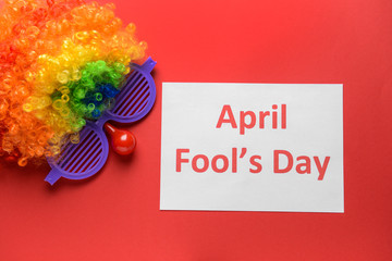 Party decor and paper sheet with text APRIL FOOL'S DAY on color background